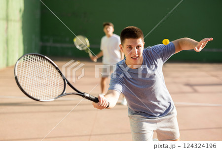 Active man with racket playing frontenis game on outdoor court Active man with racket playing frontenis game on outdoor court 124324196