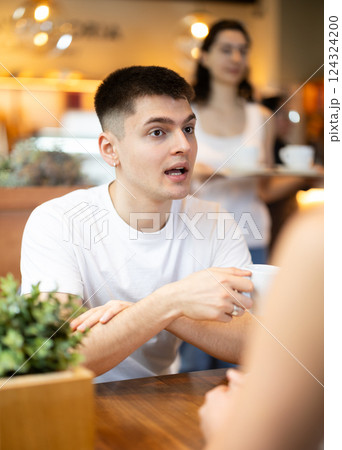 Guy in cafe sits opposite female companion, has nice conversation 124324200