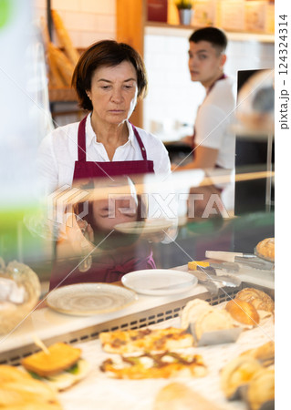 Mature woman seller laying out buns 124324314