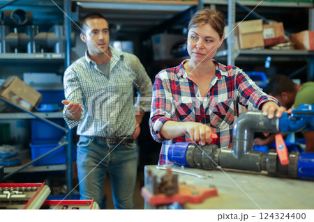 Woman fixing and assembling plumbing fixture in workshop 124324400