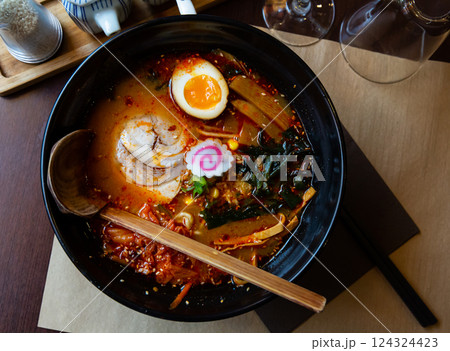Traditional japanese noodle soup with shiitake mushroom, egg and greens served in ceramic bowl with wooden chopsticks 124324423