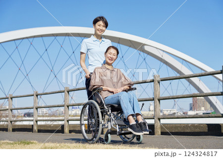 車椅子に乗った中年の女性と介護士 屋外 ポートレート カメラ目線 車椅子に乗った中年の女性と介護士 屋外 ポートレート カメラ目線 124324817