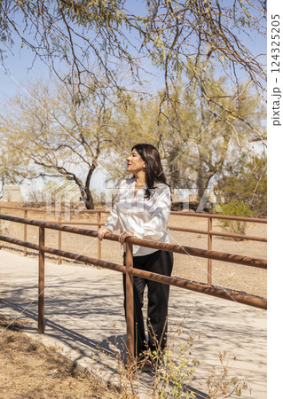 Full Length Photo Of Smiling Lebanese Woman In Her 50s in White Shirt and Black Pants Standing Outdoor, Nature, Trees On Background, Sunny Day. Beautiful Middle Eastern Attractive Female. Vertical Full Length Photo Of Smiling Lebanese Woman In Her 50s in White Shirt and Black Pants Standing Outdoor, Nature, Trees On Background, Sunny Day. Beautiful Middle Eastern Attractive Female. Vertical 124325205