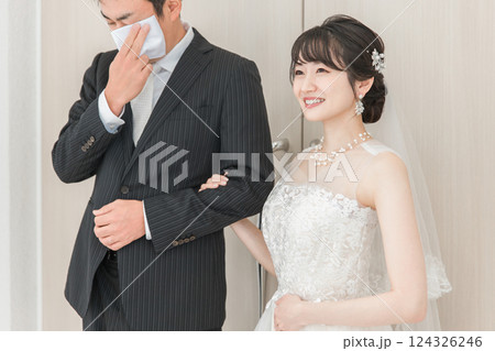 結婚式場で新郎の待つチャペルまでバージンロードを歩く新婦・花嫁の女性と涙を拭く父親 124326246