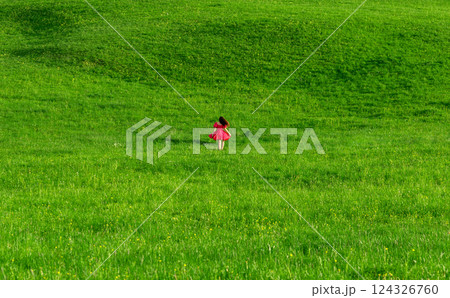 Sunset scenery with an elegant woman on a green grass meadow Sunset scenery with an elegant woman on a green grass meadow 124326760