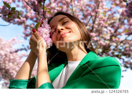 Young woman enjoys the soft cherry tree flowers 124326785