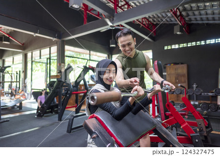 Arab middle eastern muslim woman on bench press training with an indonesian southeast asian personal trainer man at the gym. Fitness exercise and healthy lifestyle concept Arab middle eastern muslim woman on bench press training with an indonesian southeast asian personal trainer man at the gym. Fitness exercise and healthy lifestyle concept 124327475