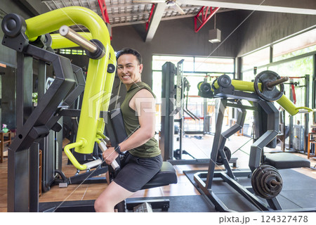 Indonesian southeast asian man training on chest press machine at the gym. Fitness exercise and healthy lifestyle concept 124327478