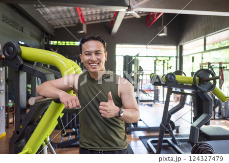 Indonesian southeast asian man showing thumb up gesture after training the gym. Fitness exercise and healthy lifestyle concept 124327479
