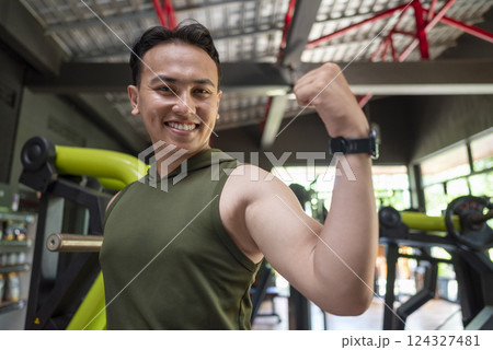 Indonesian southeast asian man showing his arm muscles after training in the gym. Fitness exercise and healthy lifestyle concept 124327481