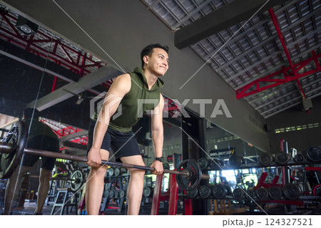 Indonesian southeast asian man working out while lifting a barbell at the gym. Fitness exercise and healthy lifestyle concept Indonesian southeast asian man working out while lifting a barbell at the gym. Fitness exercise and healthy lifestyle concept 124327521