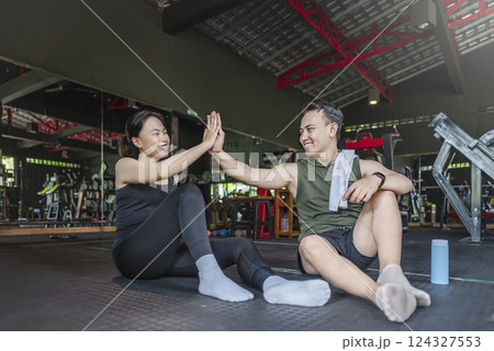 Chinese east asian woman taking a break after exercising with Indonesian southeast asian personal trainer man at the gym. Fitness exercise and healthy lifestyle concept Chinese east asian woman taking a break after exercising with Indonesian southeast asian personal trainer man at the gym. Fitness exercise and healthy lifestyle concept 124327553