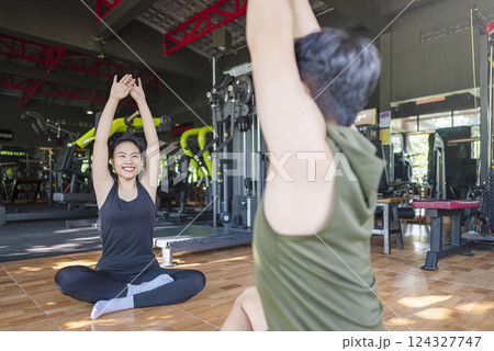 Chinese east asian woman and indonesian southeast asian man working out and stretching in a yoga class at the gym. Fitness exercise and healthy lifestyle concept 124327747