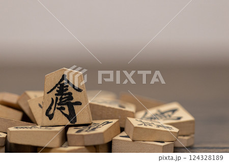 沢山の将棋の駒の上に金将が立っている　金持ちが強いイメージ 124328189