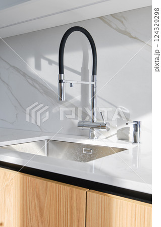 Modern kitchen design featuring a sleek faucet and elegant marble countertop Modern kitchen design featuring a sleek faucet and elegant marble countertop 124329298