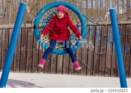 Caucasian smiling child of 8 9 years swinging on round seesaw looking at camera 124332823