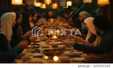 Muslim families and friends sharing iftar dinner during ramadan under ornamental lanterns Muslim families and friends sharing iftar dinner during ramadan under ornamental lanterns 124333330