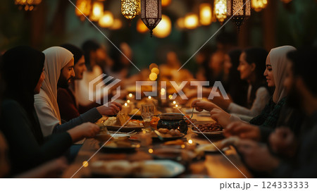 Muslim families and friends sharing iftar dinner during ramadan under ornamental lanterns 124333333