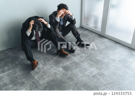 オフィスの床に座り込む二人組のミドルエイジ男性ビジネスパーソン オフィスの床に座り込む二人組のミドルエイジ男性ビジネスパーソン 124333753