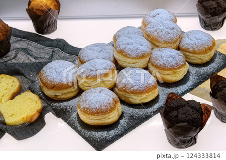 Fresh baked berliner donuts and muffins on table in cafe, top view. Fresh various pastries in bakery showcase. 124333814