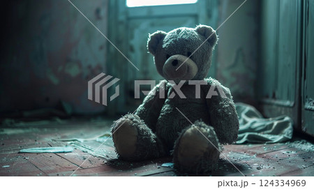 Teddy bear toy sitting alone on the floor in a room of an old abandoned house.Dramatic scary background, horror concept. 124334969