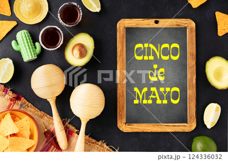 Cinco de Mayo-inspired flat lay featuring vintage chalk board, maracas, tequila shots, lime, nacho chips on a dark vintage background Cinco de Mayo-inspired flat lay featuring vintage chalk board, maracas, tequila shots, lime, nacho chips on a dark vintage background 124336032