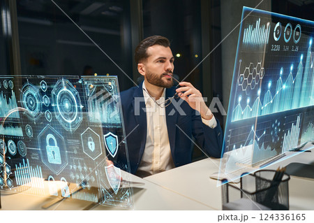 Professional Analyzing Digital Security Metrics on Futuristic Holographic Data Screens at Night 124336165