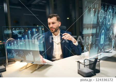 Businessman Analyzing Data on Innovative Digital Screens in a Modern Office Setting 124336172