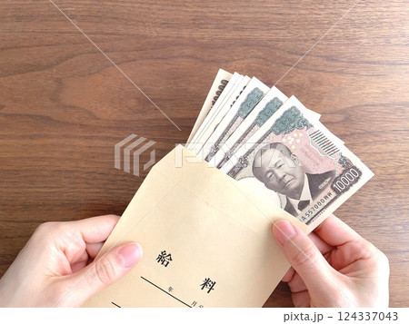 給料袋に入ったお金を持つ手元 給料袋に入ったお金を持つ手元 124337043