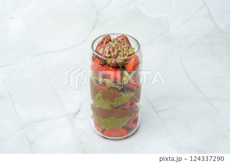 Glass filled with Dubai chocolate strawberry. Cup with kataifi, pistachio paste, milk chocolate and fresh strawberries. Street food desserts and sweets, confectionary. Copy space for text. 124337290