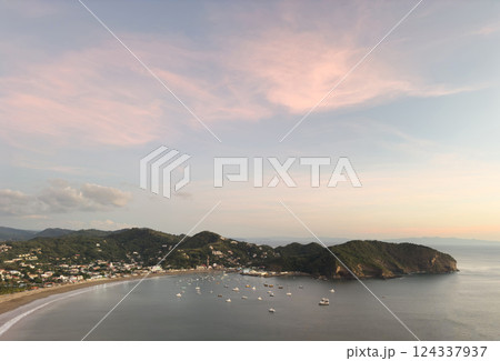 Sunset view of tranquil bay with boats and shoreline in coastal town 124337937