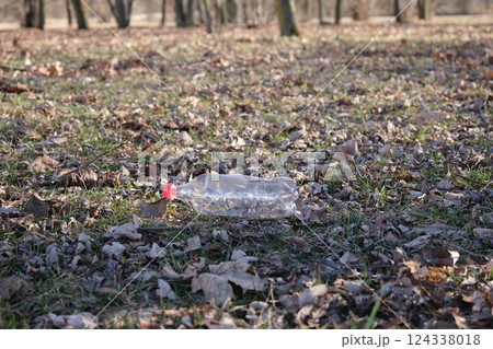 An empty plastic bottle on the ground in a city park. Environmental pollution. Environmental problem. City buildings side by side 124338018