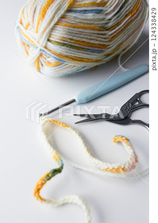 Colorful yarn ball with crochet hook and scissors on white background Colorful yarn ball with crochet hook and scissors on white background 124338429