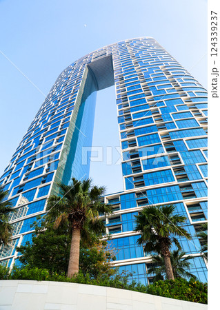 Tall modern building futuristic design and palm trees growing in the background Tall modern building futuristic design and palm trees growing in the background 124339237