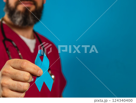 Health care professional holding blue awareness ribbon in hospital setting Health care professional holding blue awareness ribbon in hospital setting 124340400