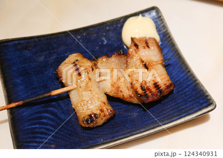 close up of Thai style grilled pork neck skewer with salad dressing on the side on a blue plate close up of Thai style grilled pork neck skewer with salad dressing on the side on a blue plate 124340931