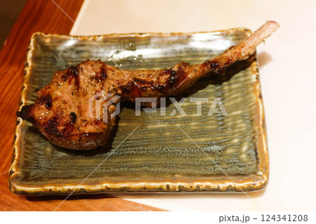 close up of grilled lamb meat mutton drumstick rack on a green plate with copy space 124341208