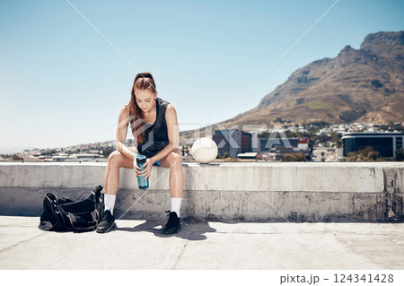 Sports athlete, woman rest on rooftop and water break after rooftop soccer training with a ball for summer fitness exercise. Urban sport player, city roof and tired after cardio football workout 124341428
