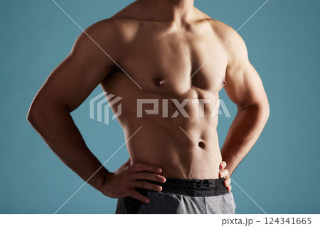 Closeup, shirtless and man in studio, muscular and fitness on blue background. Person, healthy physique and model with pecs, confidence and workout with training, bodybuilder and results for exercise Closeup, shirtless and man in studio, muscular and fitness on blue background. Person, healthy physique and model with pecs, confidence and workout with training, bodybuilder and results for exercise 124341665