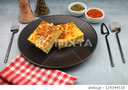 Slices of baked Round Borek cheese pie in kitchen tray with herbs. Dark background. Top view. Copy space 124344510