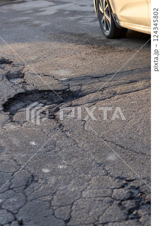 potholes in the road, holes in the asphalt on the roadway or highway.  124345802