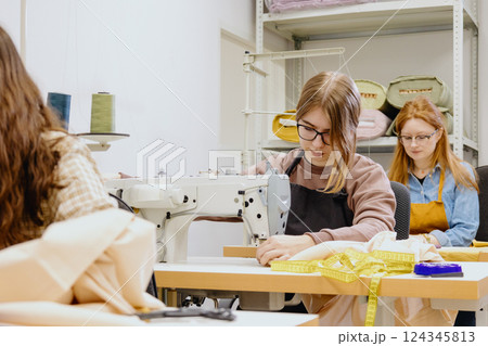 Three women sew in workshop at clothing factory. industrial equipment sewing machines. Three women sew in workshop at clothing factory. industrial equipment sewing machines. 124345813