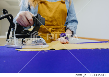 woman strokes a piece of cloth of lady in yellow apron, glasses. female fashion designer 124345817