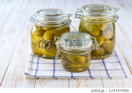 jars of pickled cucumbers on a white wooden table, selective focus. jars of pickled cucumbers on a white wooden table, selective focus. 124345900