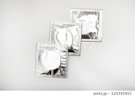 Condoms in shiny packaging on a white background. Contraceptives for men. 124345953