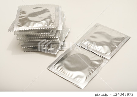 Condoms in shiny packaging on a white background. Contraceptives for men. Condoms in shiny packaging on a white background. Contraceptives for men. 124345972
