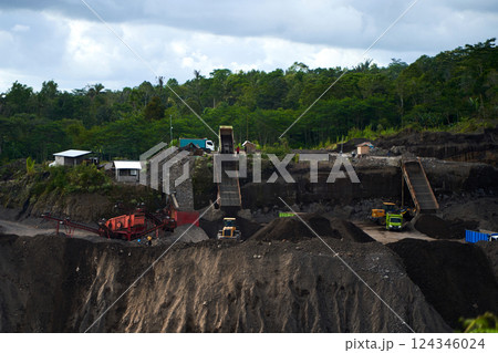 A stone quarry in Indonesia. Large equipment such as bulldozers and dump trucks are working on the site. 124346024