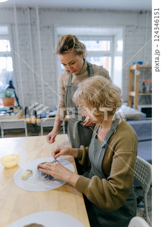 Two women work together with clay, developing skills and enjoying the artistic process. Mother and daughter engage in an art workshop, strengthening their bond through handcraft 124346151