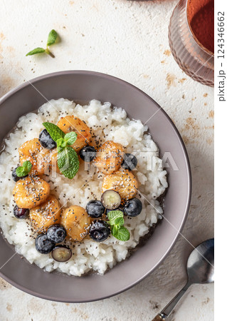 Rice porridge with banana, blueberries, chia seeds and honey sauce on a table close up, hot and healthy breakfast Rice porridge with banana, blueberries, chia seeds and honey sauce on a table close up, hot and healthy breakfast 124346662