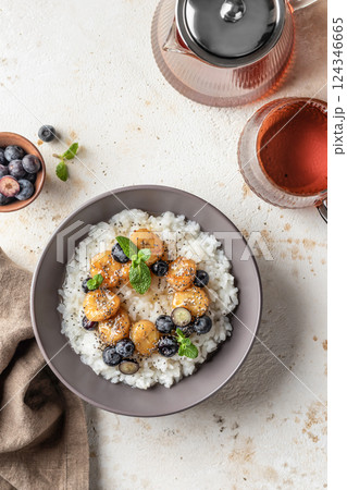 Rice porridge with banana, blueberries, chia seeds and honey sauce on a table, hot and healthy breakfast. Top view 124346665